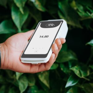 A hand holds a payment terminal.